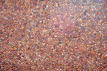 Transparent water flows down the pebbles. Pebble or gravel background or texture.