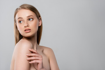pretty young woman with bare shoulders looking away isolated on grey