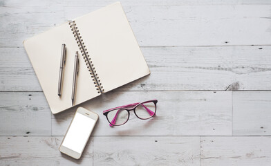Two silver pen on blank page open notebook with smartphone and glasses on white wood table nature shadow and light top view space,Business concept