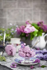 Cup of delicious homemade blueberry icecream and lilac on background