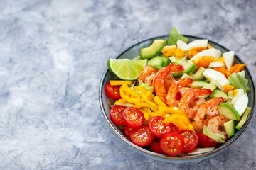 Delicious fresh salad with prawns, avocado, eggs, bell pepper, tomatoes and herbs