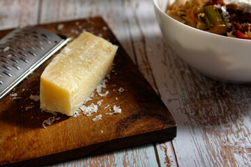 Close-up of Italian hard cheese and a cheese grater, with cheese crumbs.