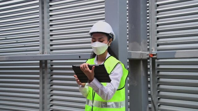 Engineer checking blueprint of industry cooling tower air conditioner is water cooling tower air chiller HVAC of large industrial building to control air system ,wearing mask for protect pollution.
