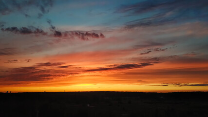 Beautiful sunset over the field and forest. The sun is reflected in the clouds. View from above. Ural Russia 2021.