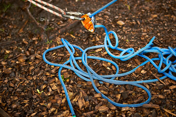 Orange grigri attached to chrome karabiner and blue rope belaying climbing equipment. Nature...