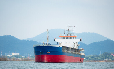 Cargo ship in the ocean with the island and mountain background,Transport ship on the sea front of dock and isle with the blue sky