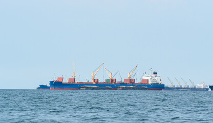 Large cargo ship red color with big crane in the blue ocean and blue sky landscape,Industrial boat in the sea logistic concept