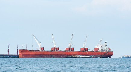 Large ship red color with big crane in the blue ocean and blue sky landscape,Industrial boat in the sea logistic concept