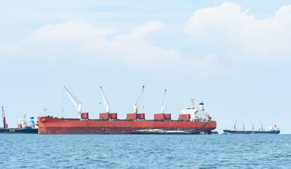 Large ship red color with big crane in the blue ocean and blue sky landscape,Industrial boat in the sea logistic concept