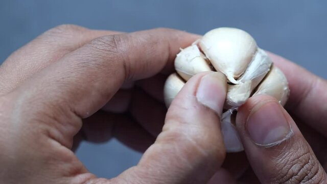 close up pf garlic on hand against pink background 