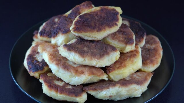 Potato cakes, ukrainian name potato zrazy, stuffed mushrooms or meat or cheese with herbs cream are fried in vegetable oil on black background, close up, rotates. Traditional Ukrainian cuisine