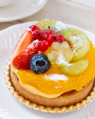 白いお皿の上のフルーツタルトとコーヒーカップのアップ