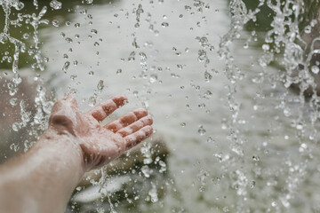 Fototapeta premium splashing water falling on a man's hand from a waterfall