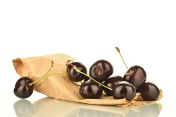 Several ripe dark red cherries with a bag of craft paper, close-up, isolated on white.