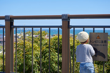 柵の前から海を見つめる子供