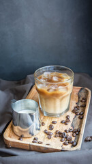 An iced coffee with milk and a milk jug  on a wooden tray and black background with a copy space.  Refreshning . 