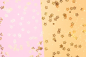 Bright glittering stars confetti scattered on a pink and gold background.
