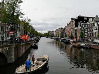 Fototapeta na wymiar Maisons traditionnelles hollandaises séparées par le canal et embarcation navigant sur le cours d'eau
