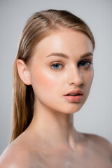 young woman with perfect skin looking at camera isolated on grey