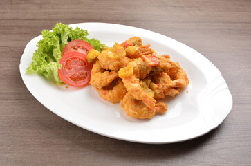 wok fried tiger prawn in salted egg yolk curry paste sauce on wood table asian halal menu