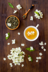 Obraz na płótnie Canvas Jasmine flowers with green tea in a cup. Overhead view