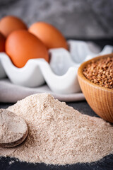 Fototapeta na wymiar fresh natural buckwheat flour on a dark stone background culinary concept