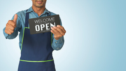 Asian man holding notice board welcome we are open sign hanging a restaurant, store, office or...