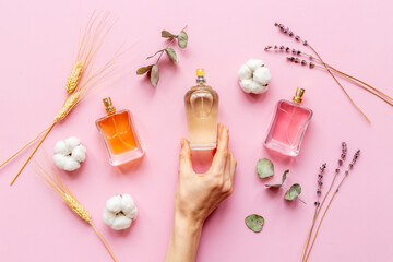 Hand holds perfume bottle with flowers flat lay