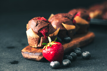 Muffin. Chocolate muffins with stawberry. Muffins on wooden stand. - obrazy, fototapety, plakaty