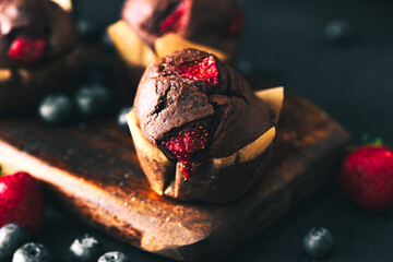 Muffin. Chocolate muffins with stawberry. Muffins on wooden stand. © Exploder
