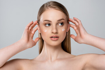 Naklejka premium pretty woman with blue eyes and cream on face isolated on grey