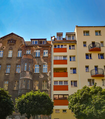 Fototapeta premium Looking up to city contrast of old tenement house and modern block of flats
