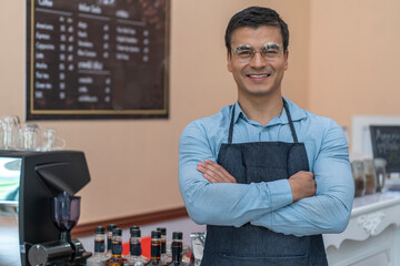 The male barista, the owner of the coffee shop, makes coffee and holds a tray of iced coffee,...