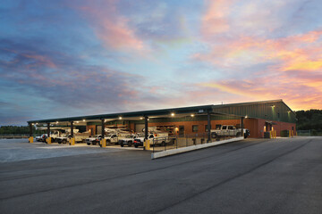Generic industrial warehouse storage building at sunset with parked trucks