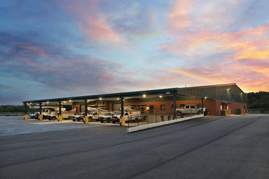 Generic industrial warehouse storage building at sunset with parked trucks