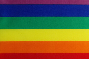 LGBT rainbow flag from fabric material with visible texture. LGBTQ rights symbol banner in visual media. Power of diversity LGBTQ+ community. LGBT pride month concept. Close Up