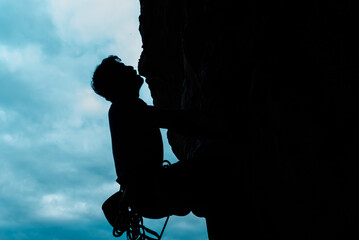 silhouette of climber climbing a mountain.