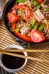 delicious glass noodles with tuna and vegetables on a dark wooden rustic background