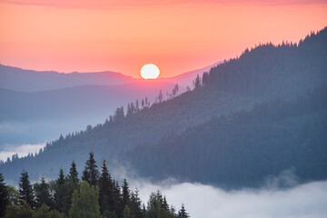 Colorful sunrise in the mountains. Bright dawn sun over the mountain tops
