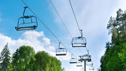 Ski lift in the summer. Chair lift with empty cabins on a sunny summer day against the blue sky.
