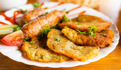 potato pancakes with fried sausages on a white plate