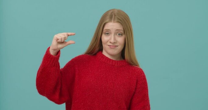 Young woman with long blond hair mocking over small size showing it with fingers.