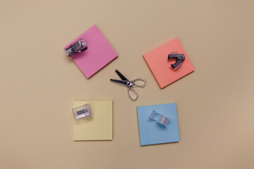 Creative back to school composition of  blank colourful sticker notes, scissors, calculator and other stationery on a yellow paper background, top view. Minimal flat lay with a copy space.