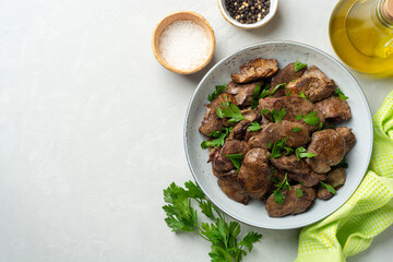 Fried chicken liver with parsley in plate on concrete background