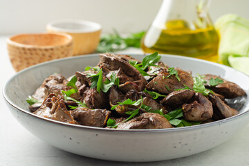 Fried chicken liver with parsley in plate on concrete background