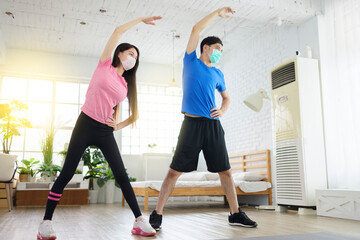 Fototapeta premium Young couple wear with medical masks and exercising at home.