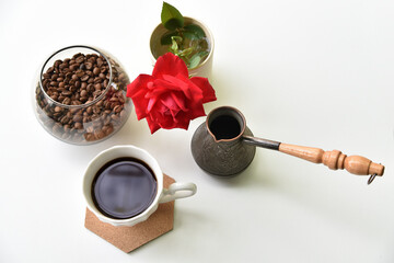 Turk, coffee mug, coffee beans and a red rose on a white background