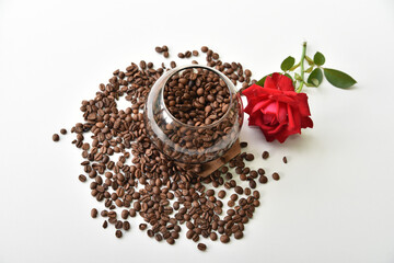 Coffee beans in a jar and a red rose on a white background