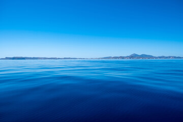 Greece. Aegean sea. Blue sky, land and calm sea water background