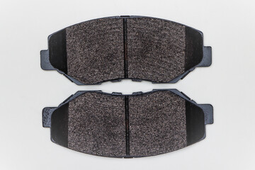 Two brake pads on a flat surface. Set of spare parts for car brake repair. Details on white...